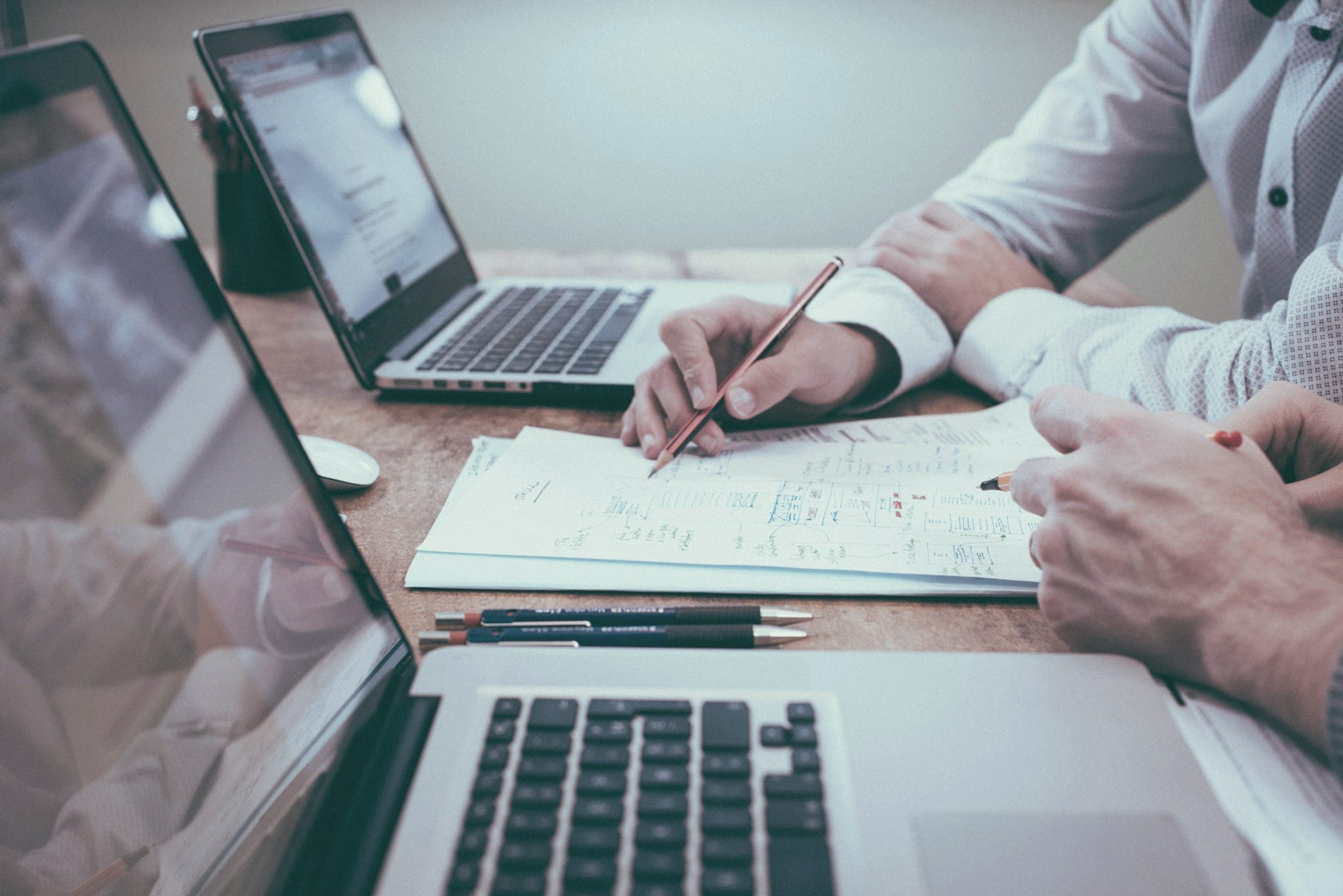 Personas revisando notas y un portátil sobre una mesa de trabajo